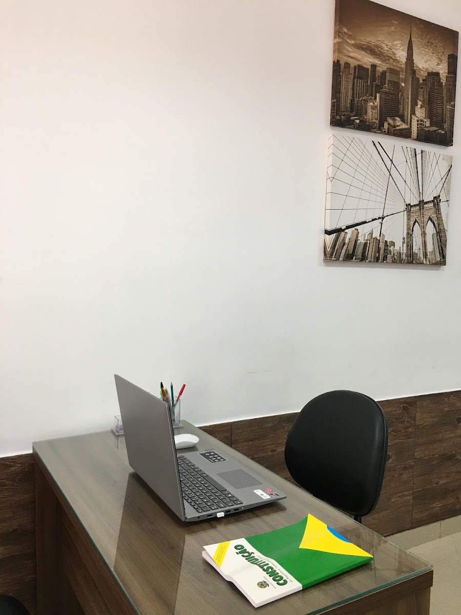 Sala de atendimento do escritório com mesa, notebook, cadeira e decoração na parede